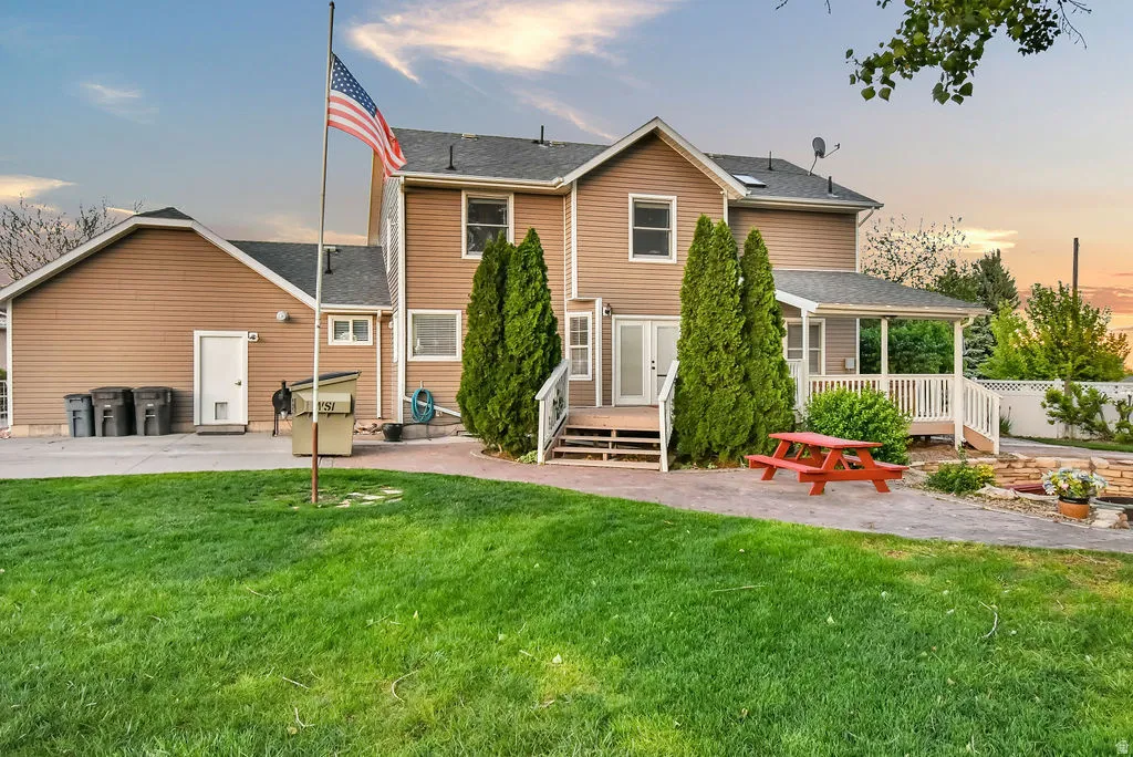 Expansive backyard featuring a manicured lawn, paved patio, and mature trees