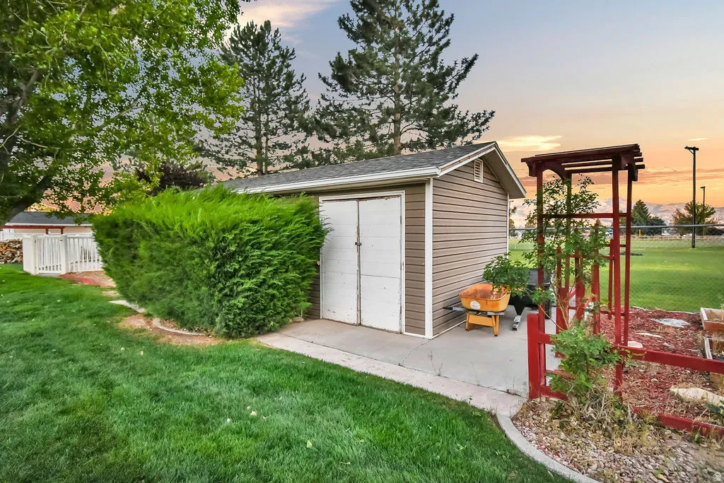 Outdoor storage shed featuring brown vinyl siding, a gray shingle roof, and double white doors