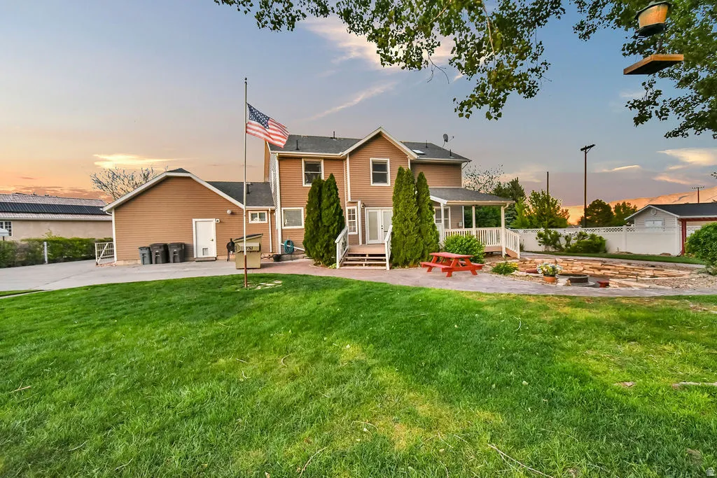 Expansive rear lawn area featuring a multi-level deck, covered porch, and a dedicated patio space with a fire pit