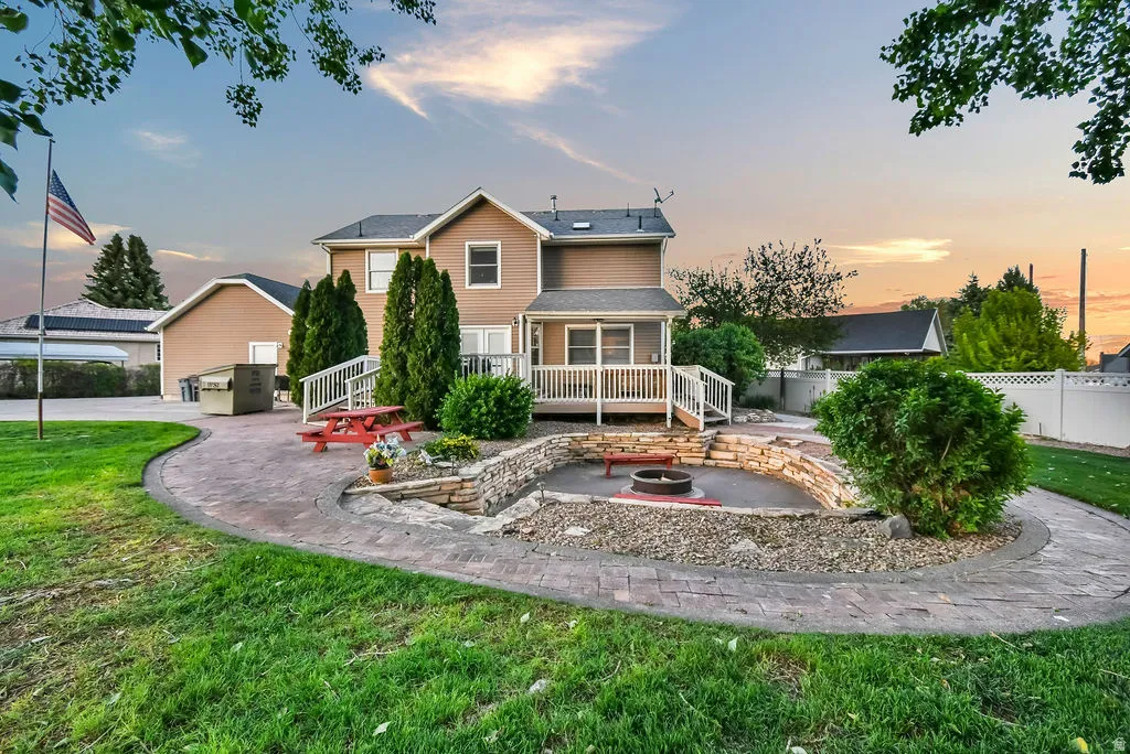 Spacious backyard featuring a stamped concrete patio, tiered stone landscaping, and a built-in fire pit