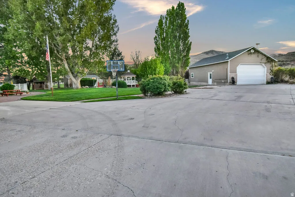 Expansive concrete driveway with a basketball hoop, offering abundant outdoor space