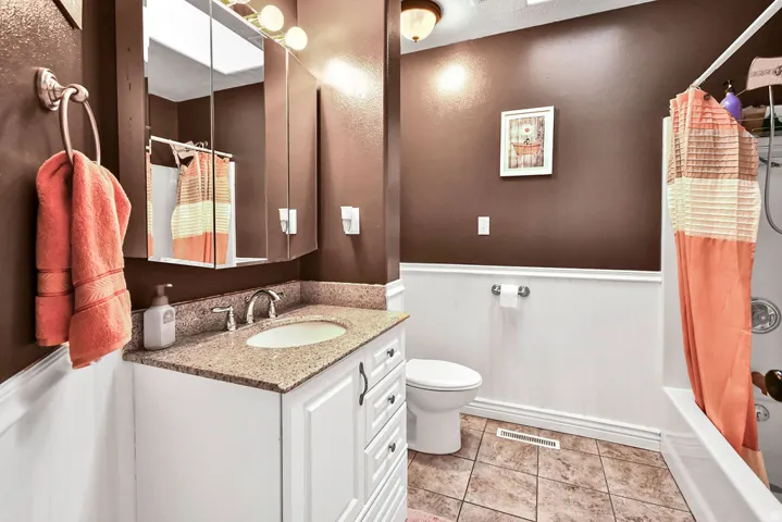 Bathroom featuring a white vanity with a granite-look countertop, an integrated sink, and brushed nickel fixtures