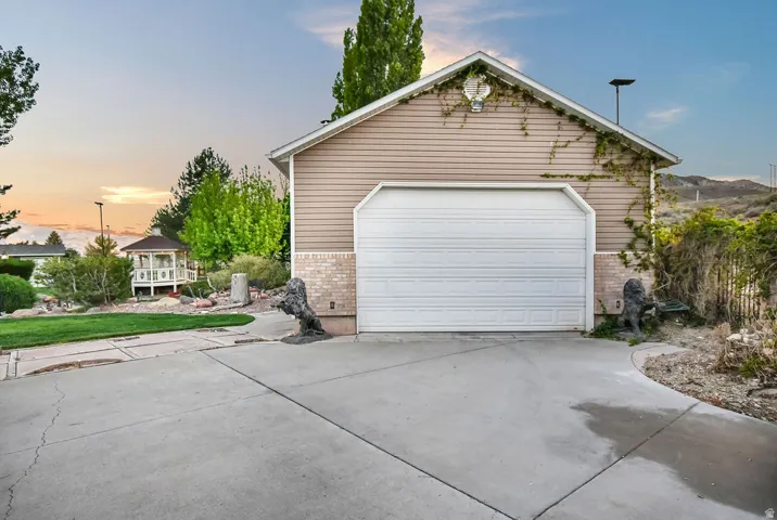 Single-car garage with a white sectional door, beige siding, and brick veneer