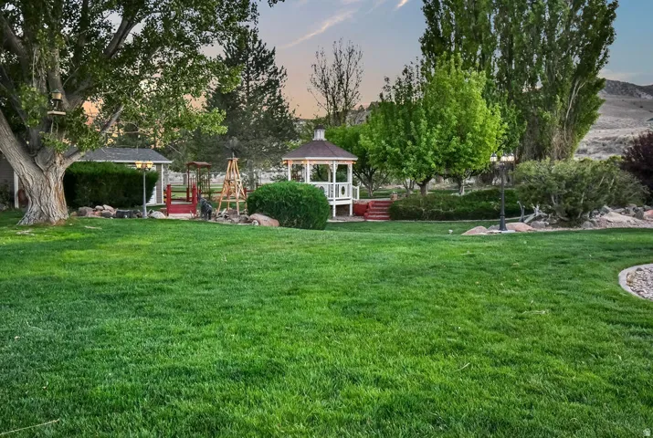 Expansive green lawn with mature trees and a white gazebo