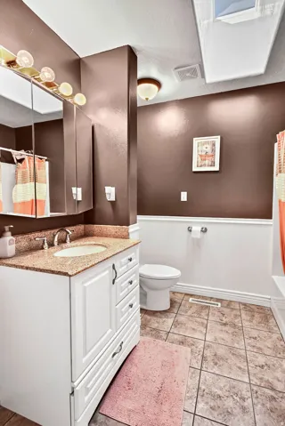 Bathroom featuring a white vanity with a light-toned countertop, a surface-mounted sink, and a mirrored medicine cabinet