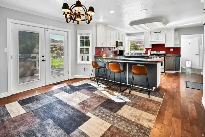Kitchen featuring white upper cabinetry, a dark lower island with seating, and stainless steel appliances