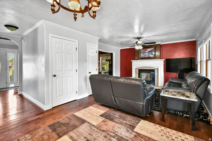 Living area featuring rich wood-finish flooring, a white mantel fireplace with stone surround, and windows providing natural light