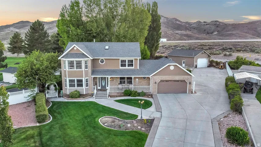 Traditional-style home featuring a two-car attached garage, expansive concrete driveway, and a detached auxiliary garage