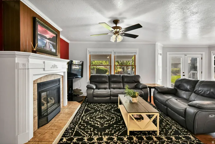 Living area featuring a white mantel fireplace with tile surround, wood-finish flooring, and crown molding
