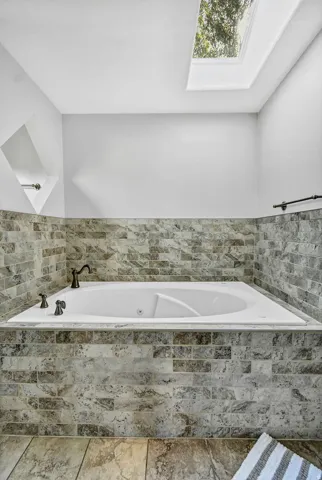 Built-in soaking tub with dark-toned fixtures and a tiled surround