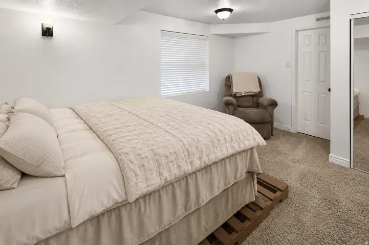 South East Downstairs Carpeted room featuring a window with blinds, white walls, and a ceiling-mounted light fixture