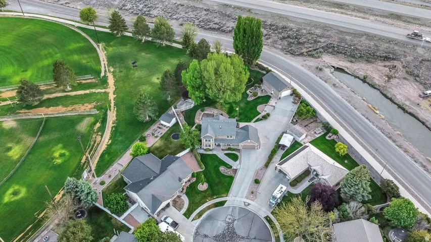 Aerial perspective showcasing a property with extensive landscaping, a paved driveway, and mature trees