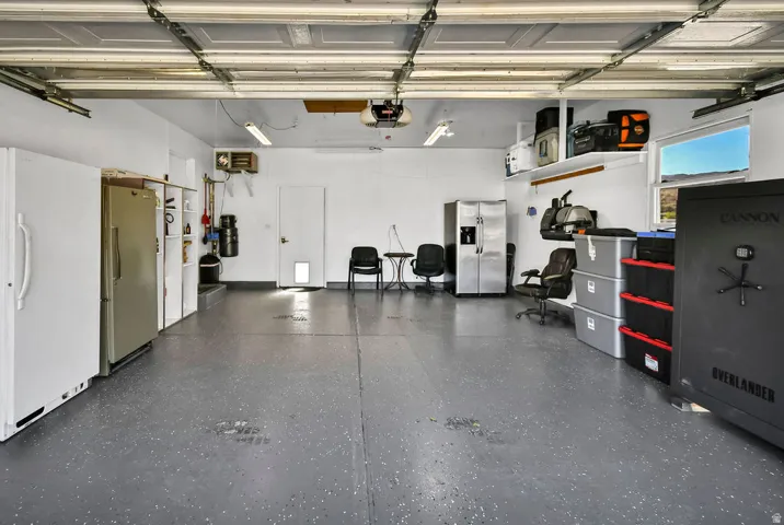 Spacious two-car garage featuring a gray epoxy-coated floor, overhead fluorescent lighting, and white painted walls