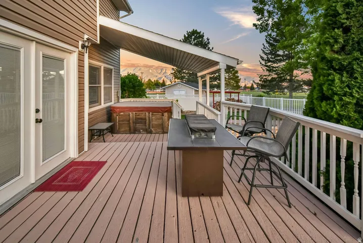 Spacious outdoor deck featuring composite decking, white railing, and a covered patio area
