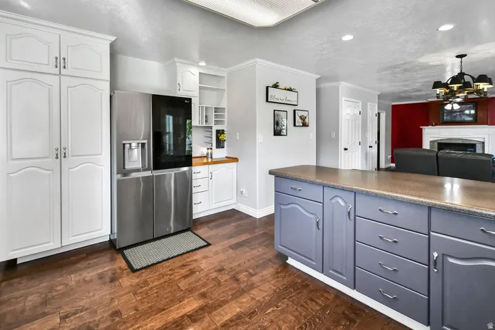Kitchen featuring wood-finish flooring, an expansive island with gray cabinetry, a stainless steel refrigerator, white wall cabinetry, and recessed ceiling lighting