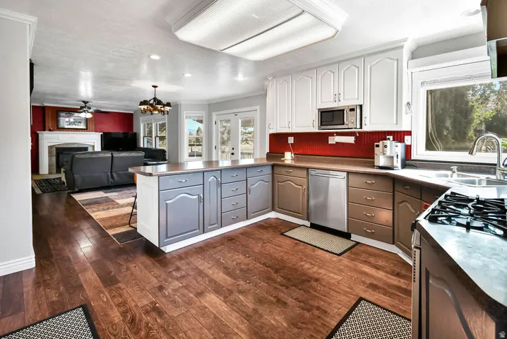 Kitchen featuring wood-finish flooring, white upper cabinetry, a stainless steel dishwasher, and a built-in microwave