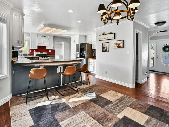 Kitchen featuring white upper cabinetry, dark lower cabinetry, and a central island with countertop seating