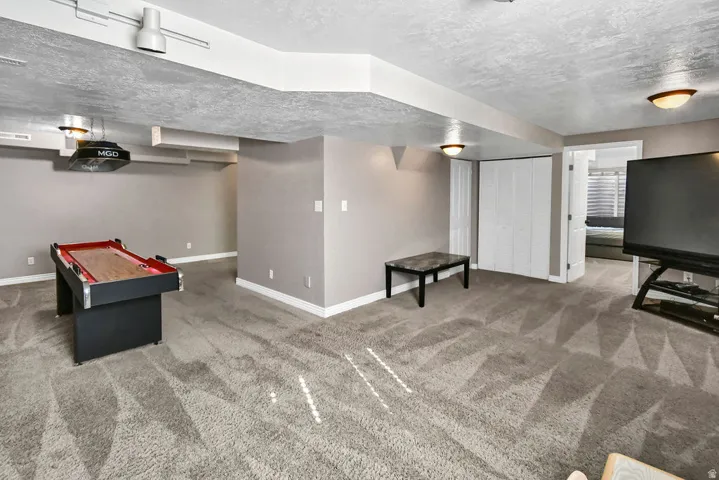 Spacious carpeted room featuring track lighting and ceiling-mounted fixtures