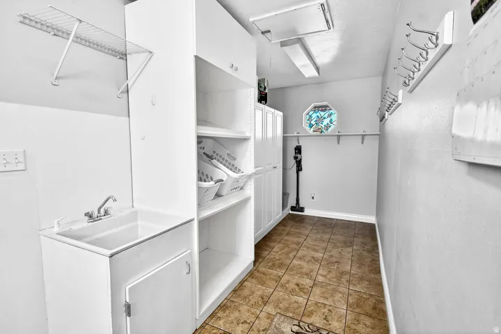 Utility room featuring a built-in sink with storage cabinetry, integrated shelving units, a wall-mounted drying rack, and a unique octagonal window