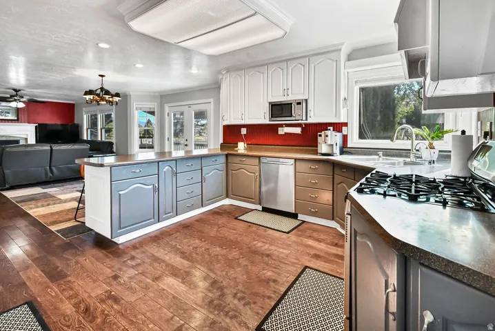 Expansive kitchen featuring wood-finish flooring, an island with storage, white upper cabinetry, and a built-in microwave