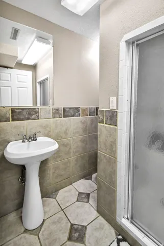 Pedestal sink with chrome fixtures, complemented by a large wall mirror