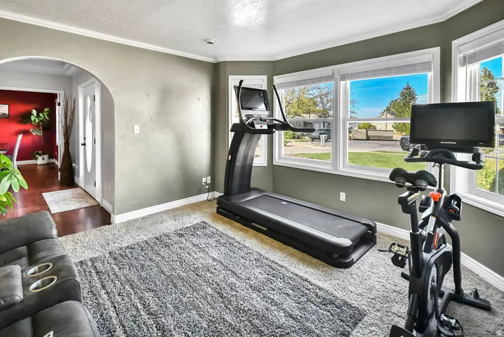 Spacious room featuring multiple large windows, wall-to-wall carpeting, and an arched doorway