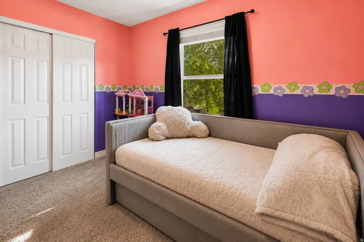 Carpeted room featuring a white bi-fold closet and a window with dark drapes