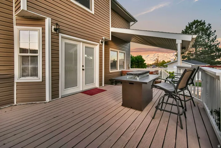 Expansive outdoor deck featuring wood-finish flooring, white railing, and a partial overhead cover