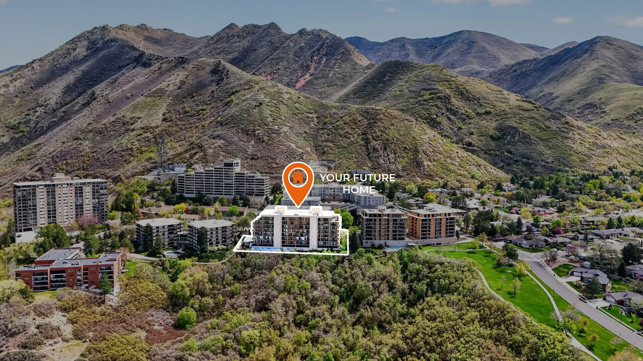 Aerial perspective showcasing a modern multi-story building surrounded by mountainous terrain and established residential areas