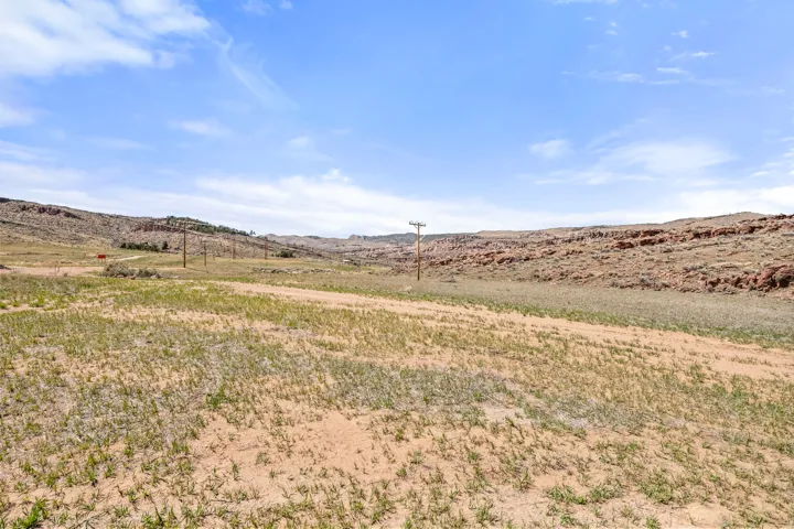 Expansive open landscape featuring a dirt track, sparse ground cover, and distant rock formations