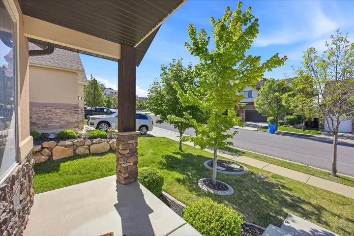 Front porch with a stone-accented column, concrete flooring, and an overhead soffit