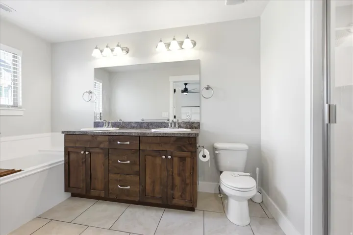 Bathroom featuring a double vanity with wood-finish cabinetry, a large mirror, and a built-in bathtub