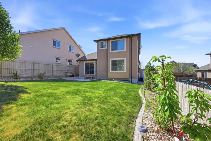 Expansive backyard featuring a manicured lawn, concrete patio, and full privacy fencing