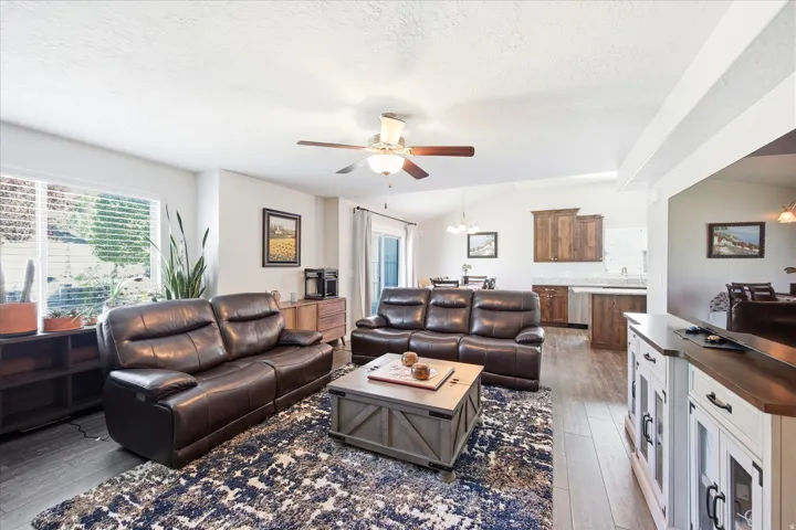 Open-concept living area featuring vaulted ceilings, wood-finish flooring, and a ceiling fan