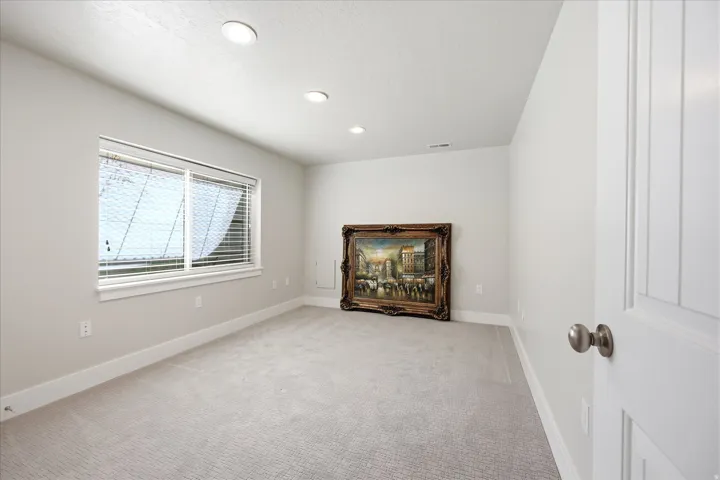 Spacious room featuring light-colored walls, recessed ceiling lighting, and wall-to-wall carpeting