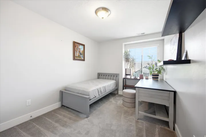 Bright room featuring a window with blinds, light gray carpeting, white baseboards, and a flush-mount ceiling light fixture