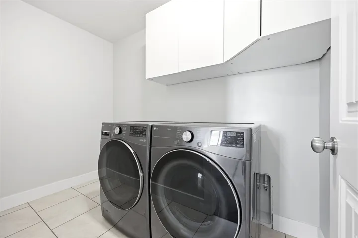 Laundry area featuring white cabinetry, tile flooring, and a white paneled door with brushed nickel hardware