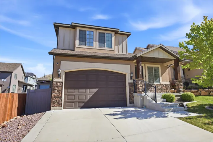Contemporary facade featuring a prominent two-car garage, stone accents, and a covered entry