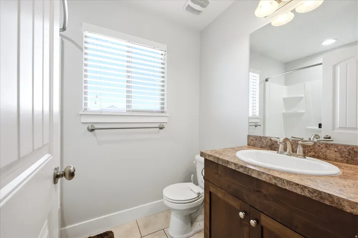 Bathroom featuring a wood-finish vanity with an integrated sink, a speckled countertop, and brushed nickel fixtures