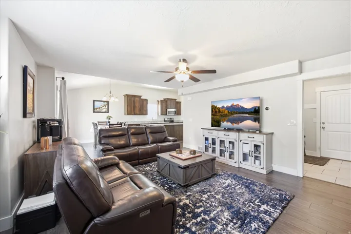 Spacious living area featuring wood-finish flooring, a ceiling fan, and recessed lighting