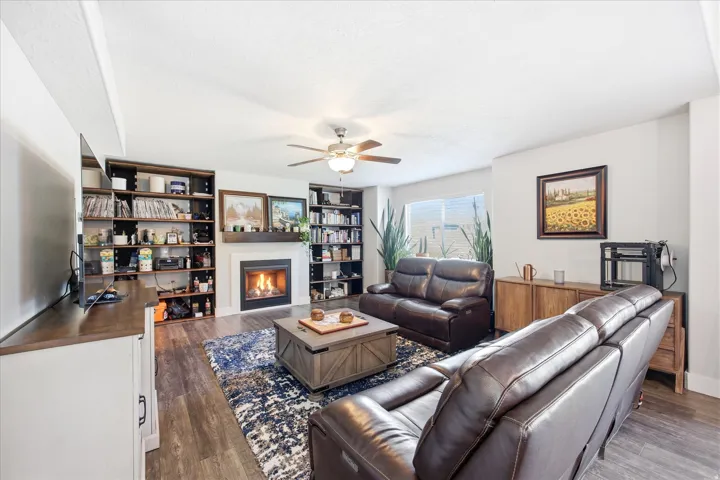 Living space featuring wood-finish flooring, a built-in fireplace with a white mantel, and surrounding built-in shelving