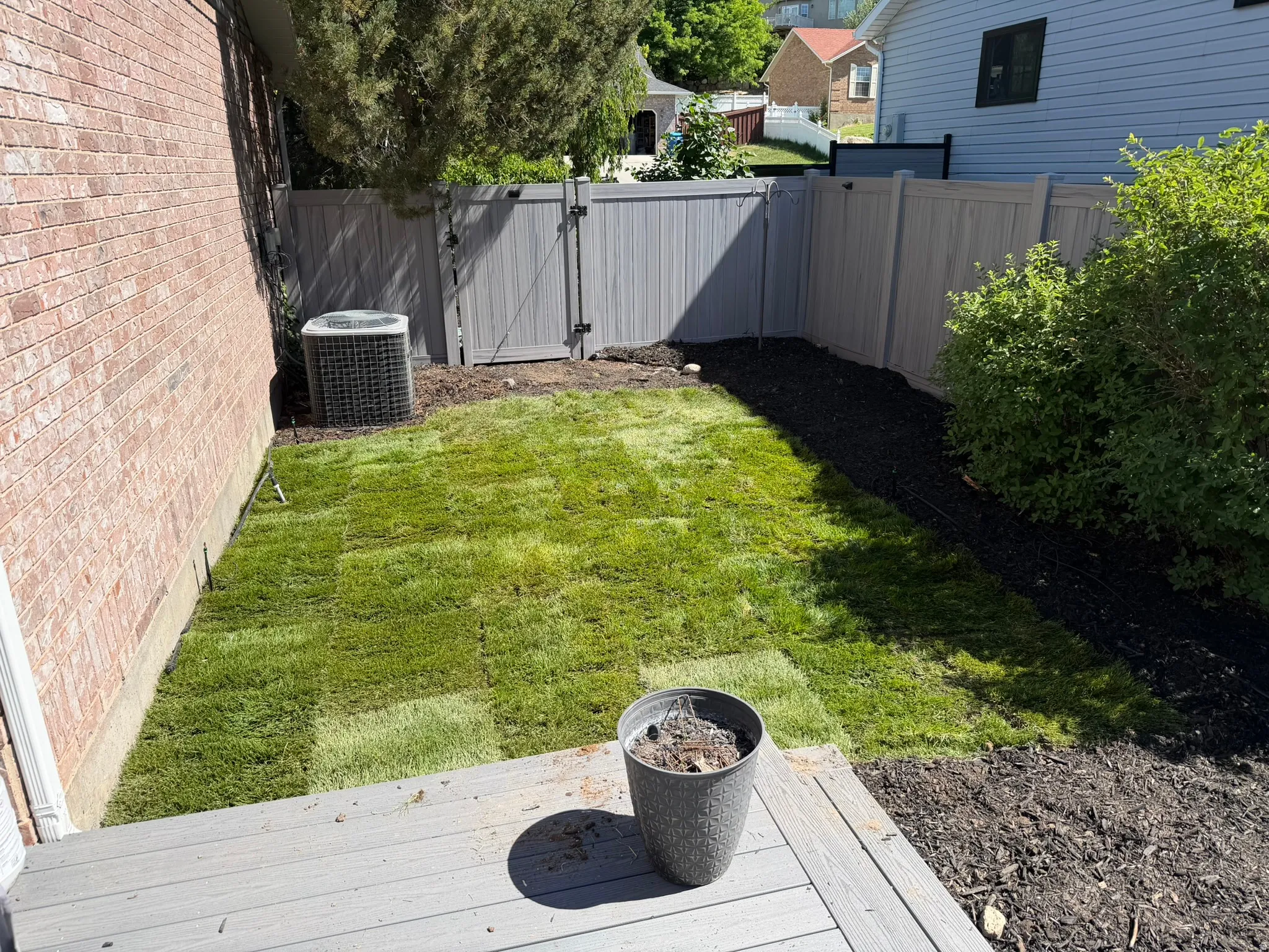 Backyard space featuring a newly sodded lawn, wood-finish decking, and a privacy fence