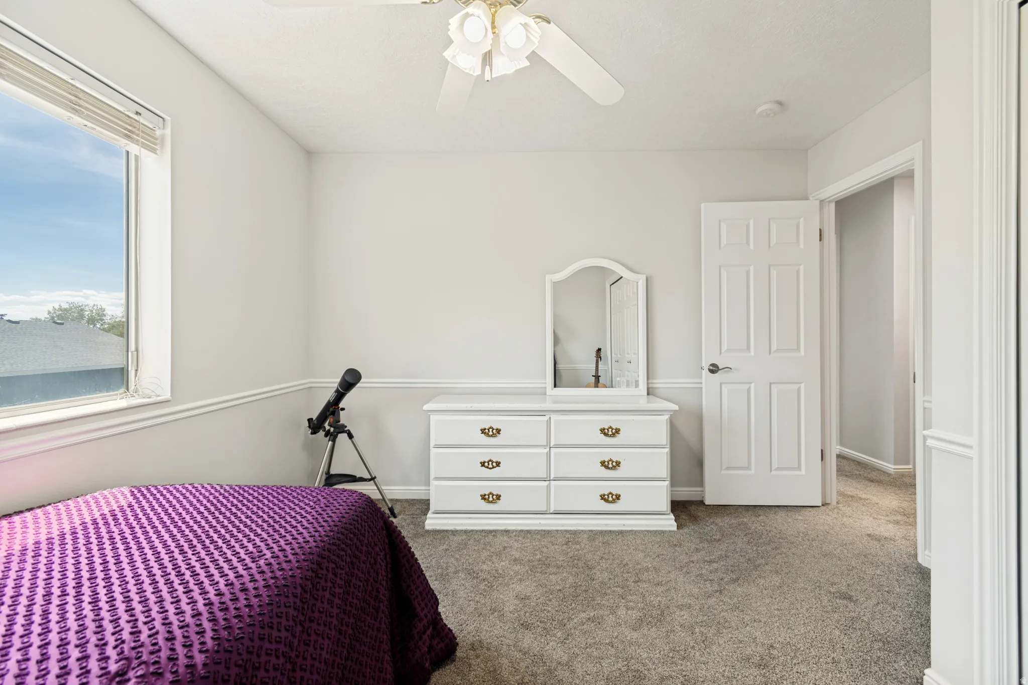 Bright room featuring a large window, neutral wall paint, white trim, and a ceiling fan
