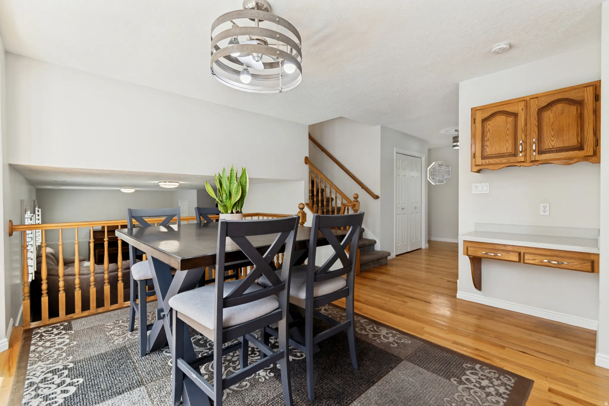 Dining area featuring wood-finish flooring, a contemporary chandelier, and a built-in wood desk with upper cabinetry