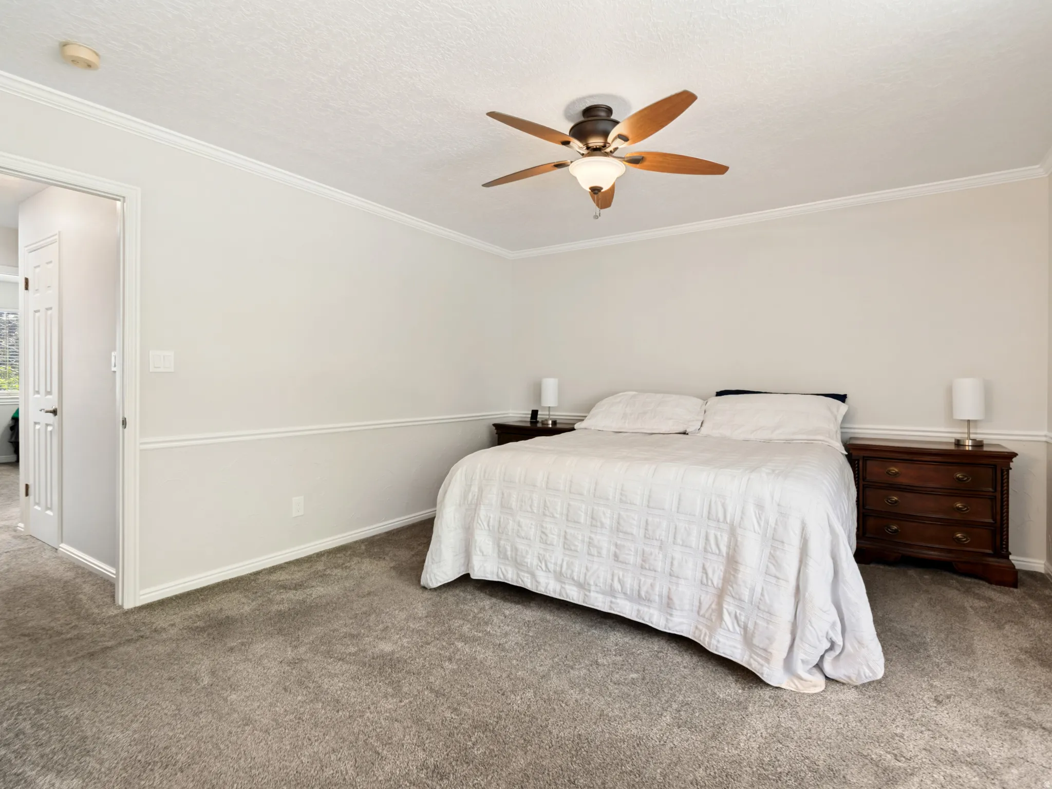 Primary Suite: Plush gray carpeting throughout, featuring white crown molding and chair rail detailing