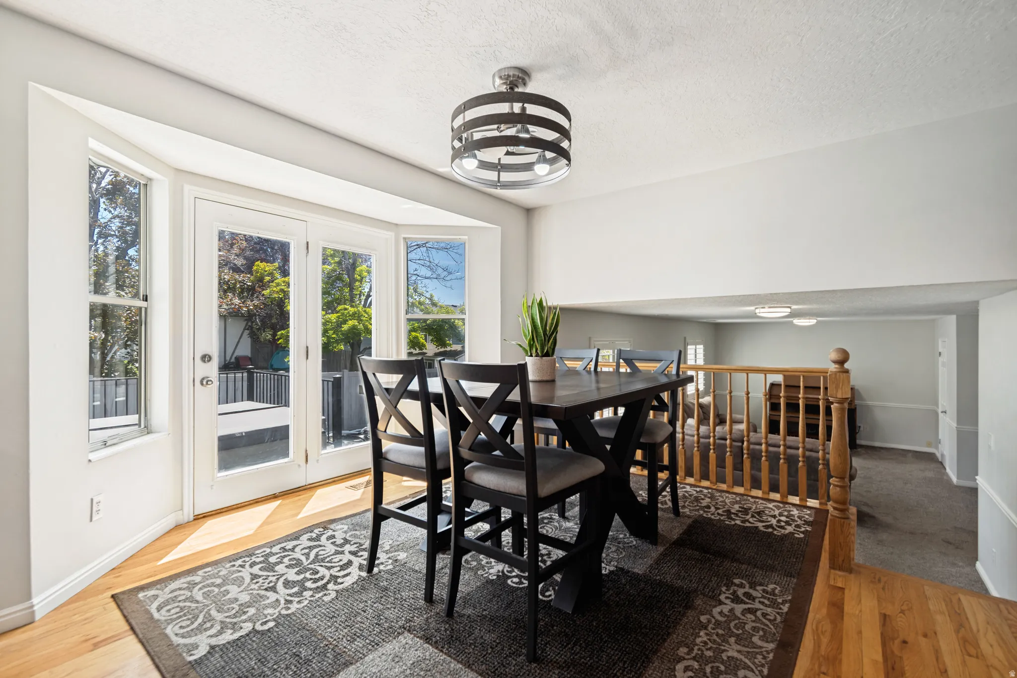 Dining area featuring wood-finish flooring, a bay window with French doors, and a decorative pendant light fixture