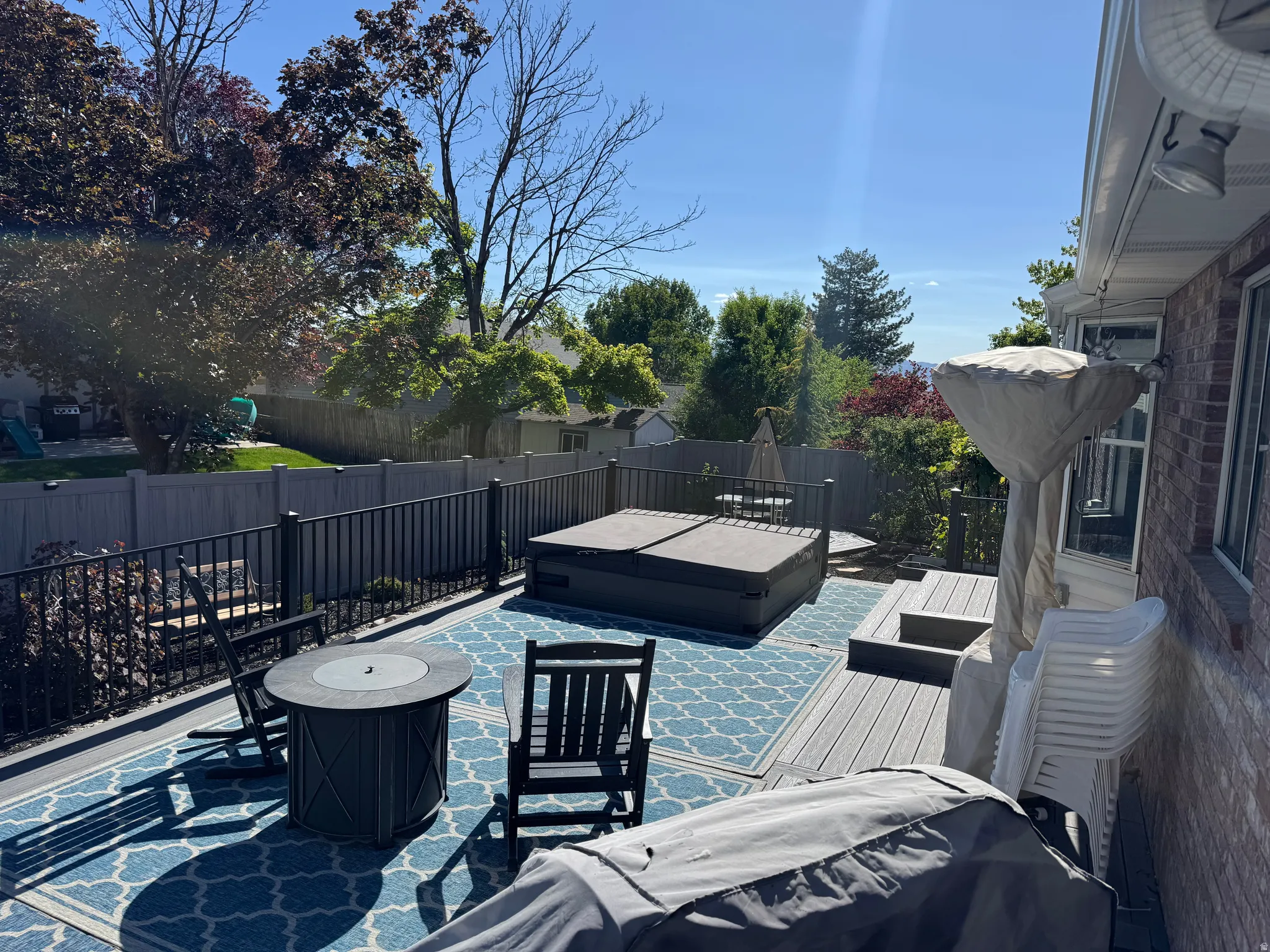 Expansive composite deck featuring a built-in hot tub (INCLUDED), black metal railings, and a fire pit. HOT TUB Is new this year.