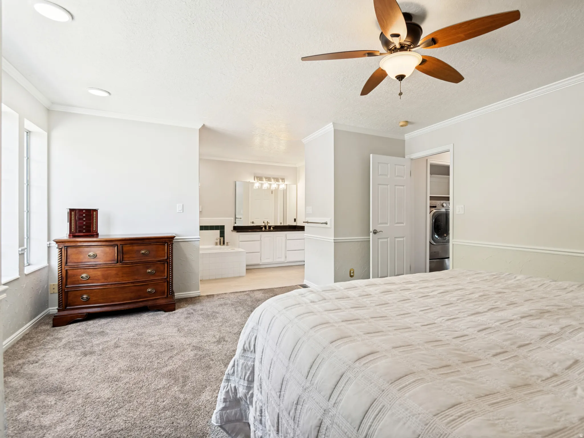 Primary Suite: Carpeted room with a ceiling fan, crown molding, and recessed lighting