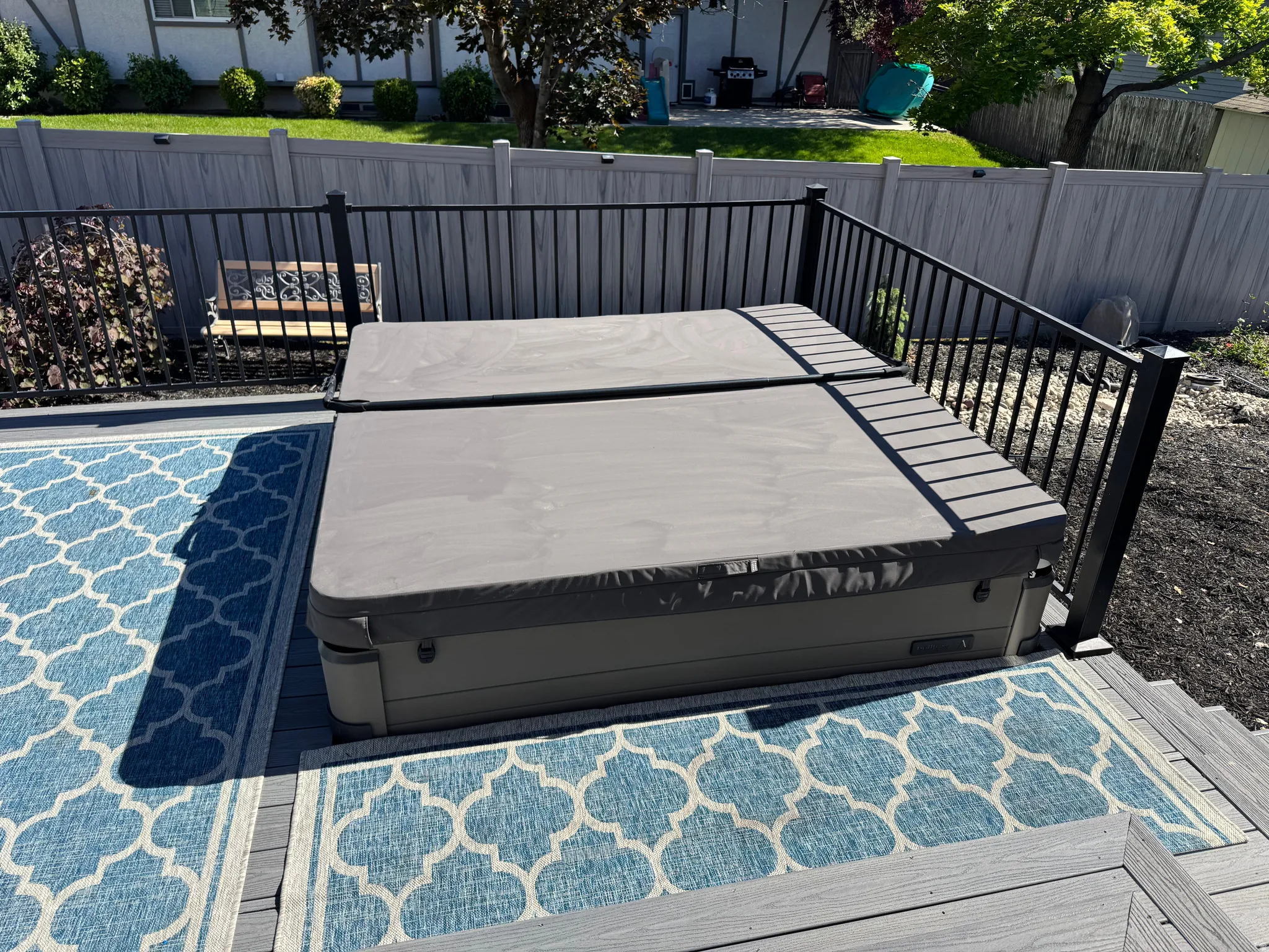 Composite deck featuring a built-in HOT TUB included with a protective cover, black metal railings, and a privacy fence. Hot Tub not even one year old!