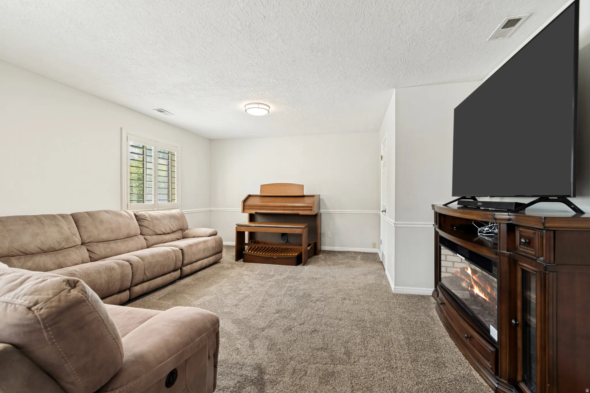 Carpeted living space with white walls and crown molding